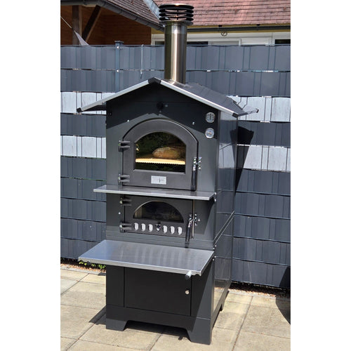 Holzbackofen Gusto Fontana 80x45 freistehend im Garten platziert vor einem klassischen Gartenzaun, ideal für den Außenbereich.